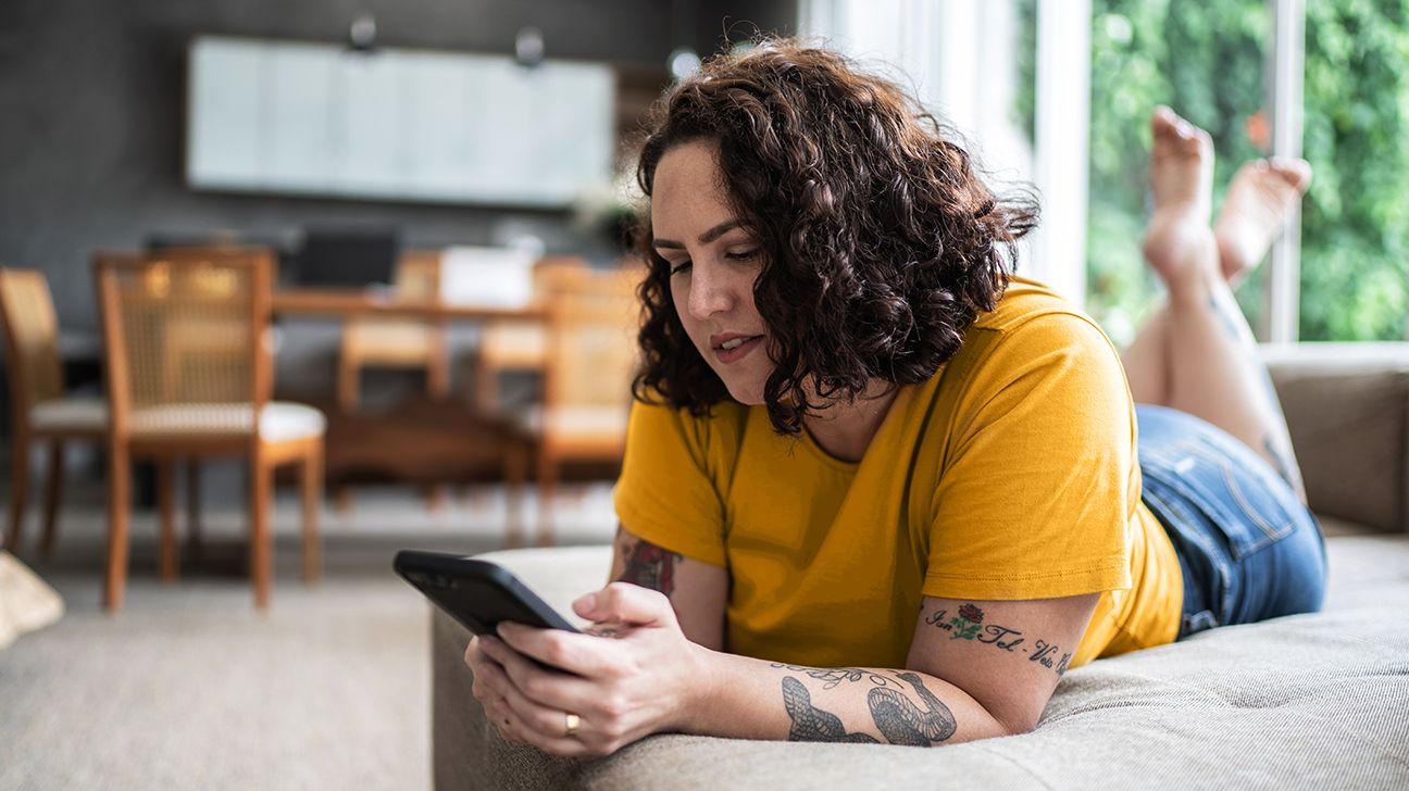 A photograph of a woman browsing on her phone, looking for where to buy Ozempic online.